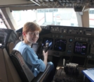 Young Adrien sitting in the cockpit of an airliner holding Yoke