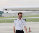 Adrien walking under wing of Cessna with sunglasses on