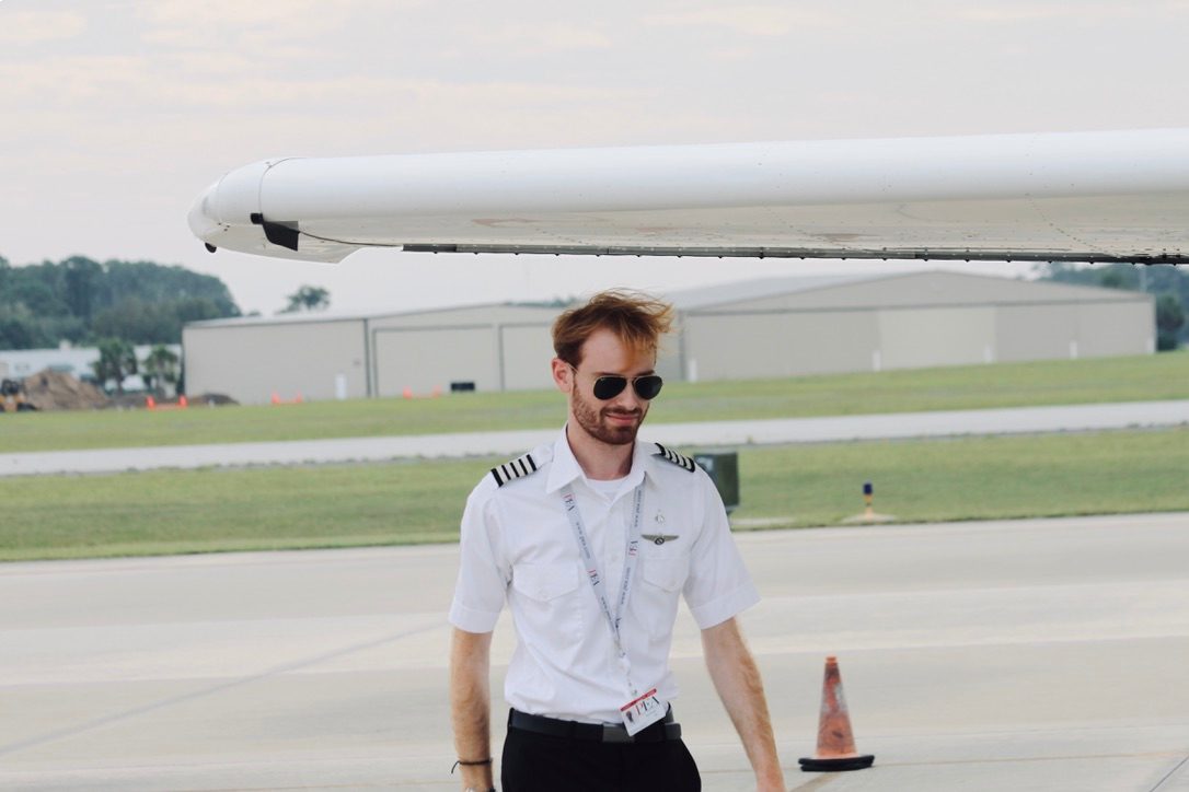 Adrien walking under wing of Cessna with sunglasses on