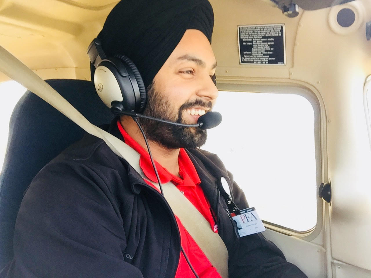 Dhingra side profile shot of him smiling with red polo and headset on, while flying