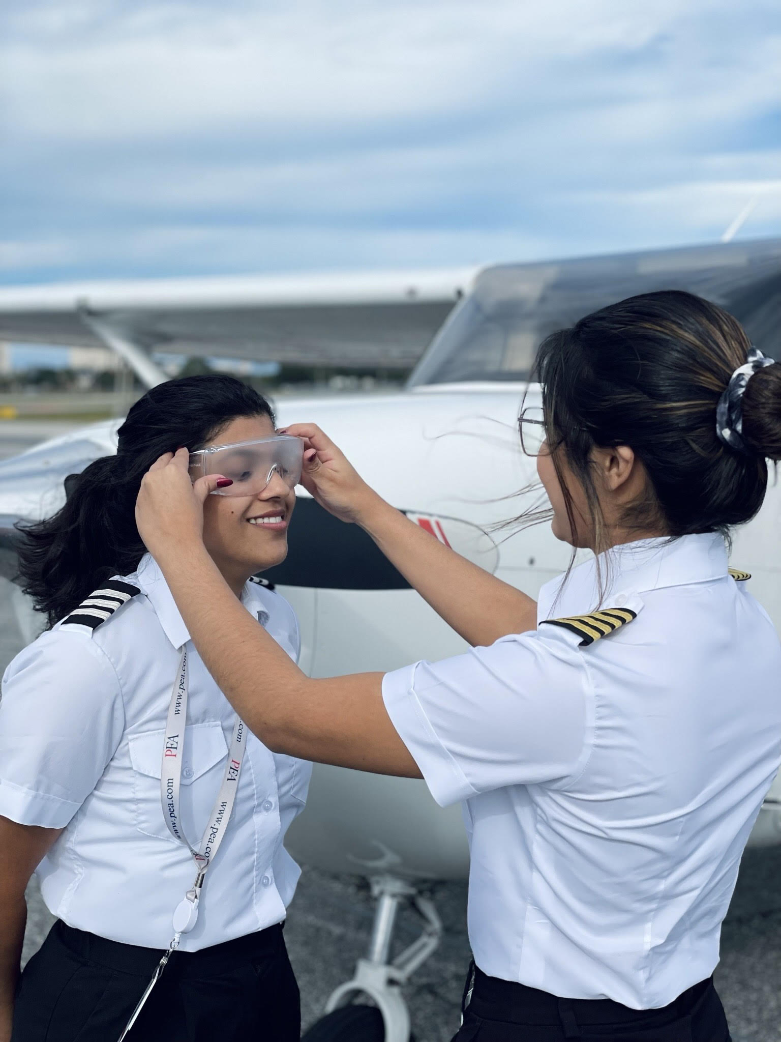 Xochitl Guerrero on the right hand side with CFI Gold Stripes on, putting Instrument Foggles on one of her students