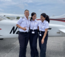 Xochitl in the middle of two friends in front of a Cessna 172 on KFIN ramp