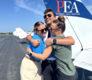 Sara Mohlin (R), Tegvir Anand (M), and Amelie Coleman(R) hugging in front of PEA Cessna 172 tail on KFIN tarmac during Teg_s last day at PEA