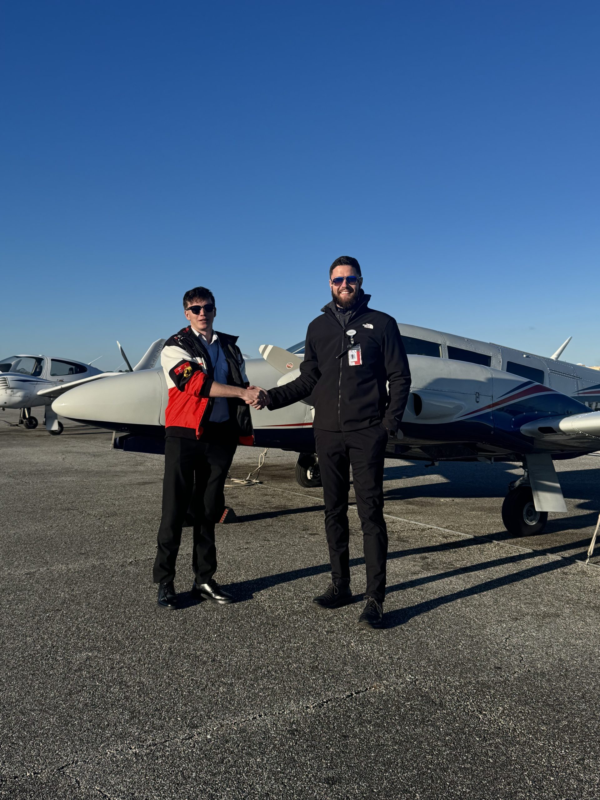 Dan Zagorii (R) shakes hand with his student Jack Haddican (L) in front of Piper Seneca to celebrating Haddican's accomplishment
