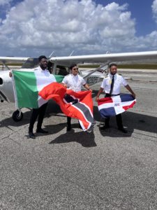 Dhaarinesh Balkisoon in the middle holding a Trinidad and Tobago flag with 2 other instructors