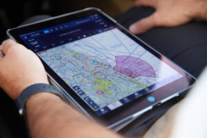 a pilot holding an ipad with flight signals displayed on it.