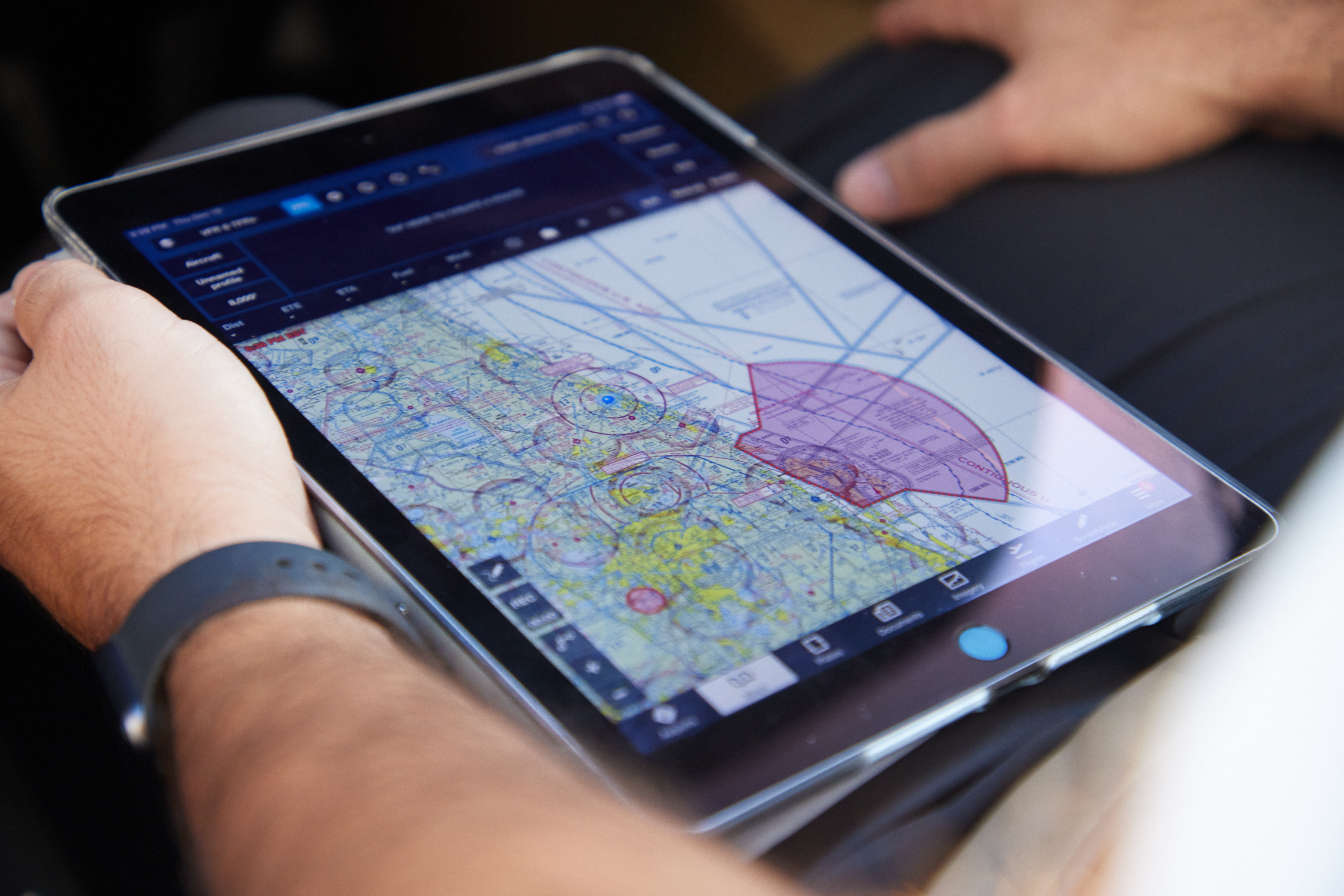 a pilot holding an ipad with flight signals displayed on it.