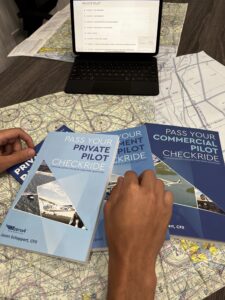 a stack of booklets: "Pass Your Private Pilot Checkride" and "Pass Your Commercial Pilot Checkride"