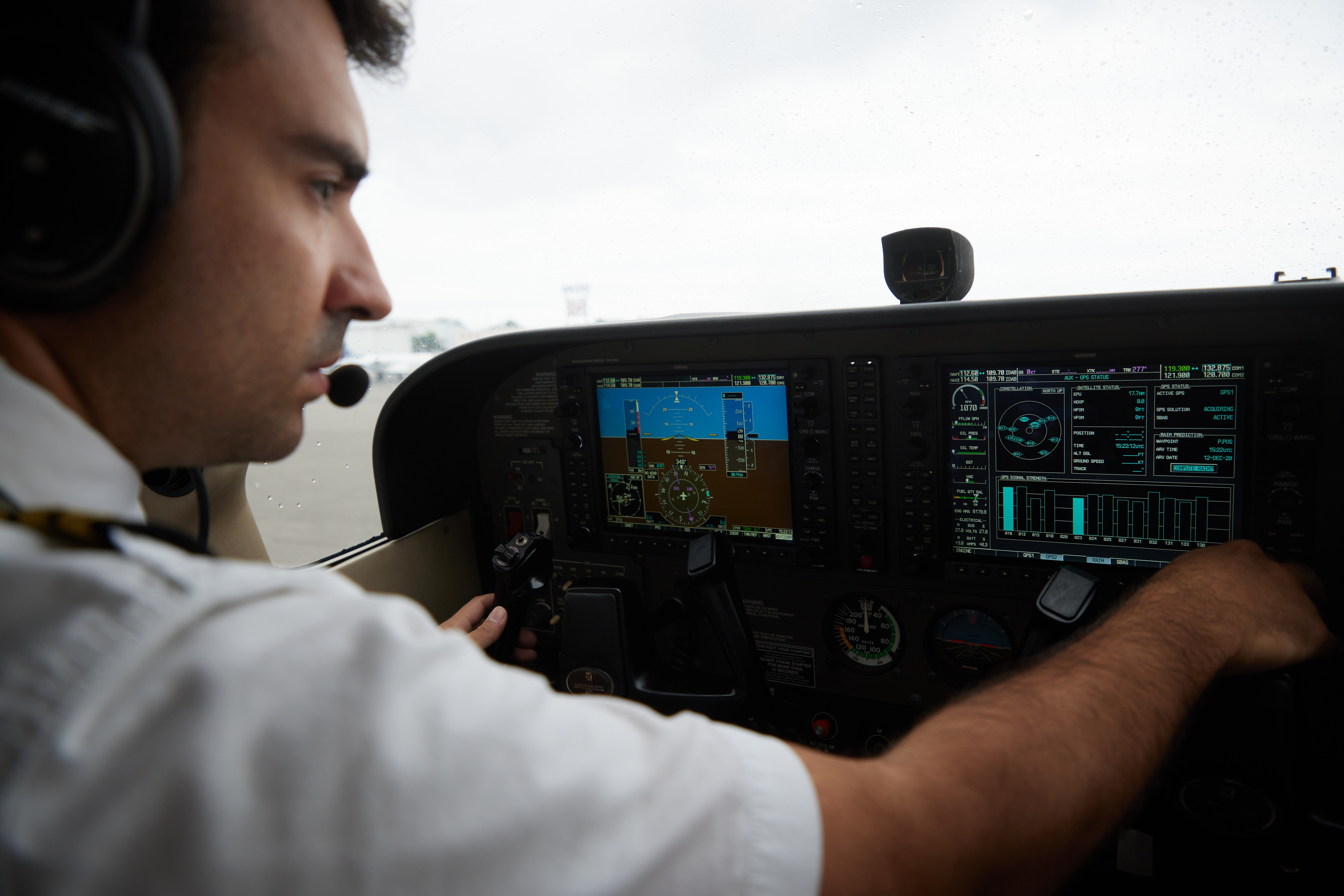 Pilot adjusting avionics controls inside a modern aircraft cockpit during preflight or flight operations.