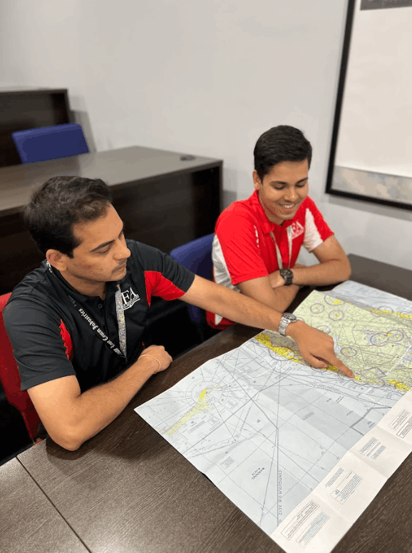 Flight instructor reviewing an aeronautical chart with a student pilot during classroom navigation training.